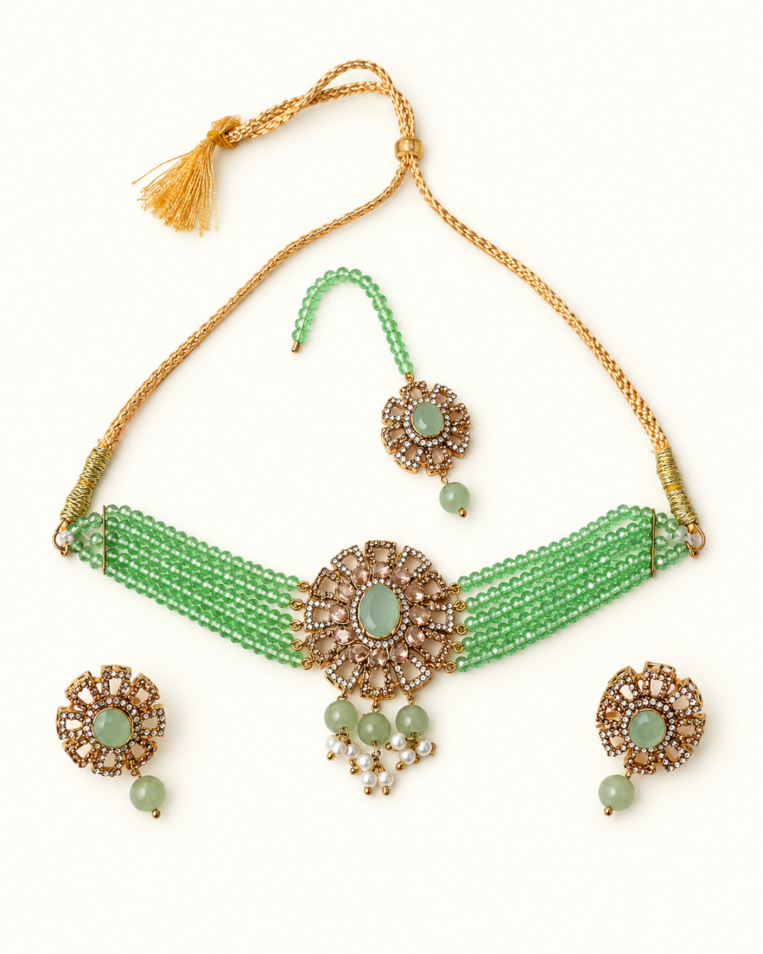 Green beaded necklace set with gold-plated metal details, featuring a choker necklace, matching earrings, and a maang tikka, arranged on a plain white background.