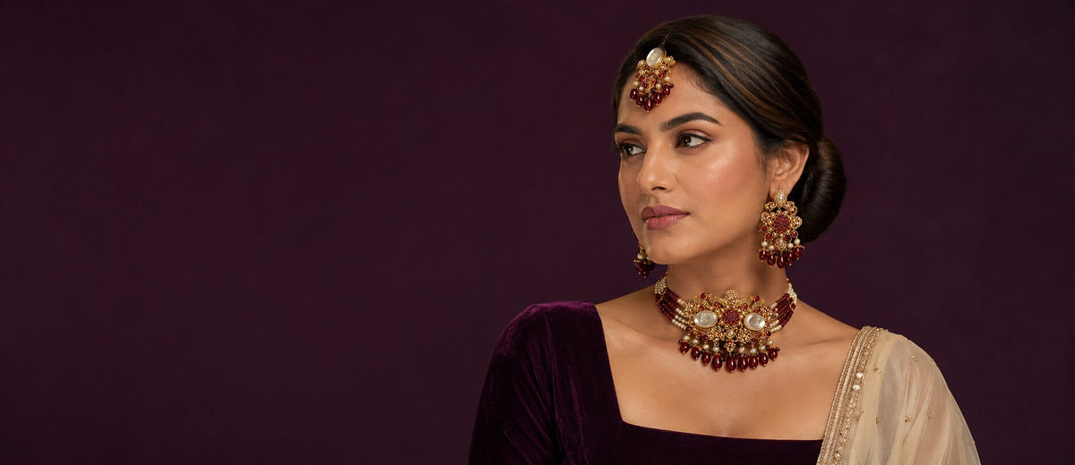 Pakistani woman wearing a gold, pearl and deep red bridal choker set from Zurein